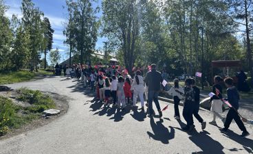 en gruppe mennesker som går på en vei med trær på hver side