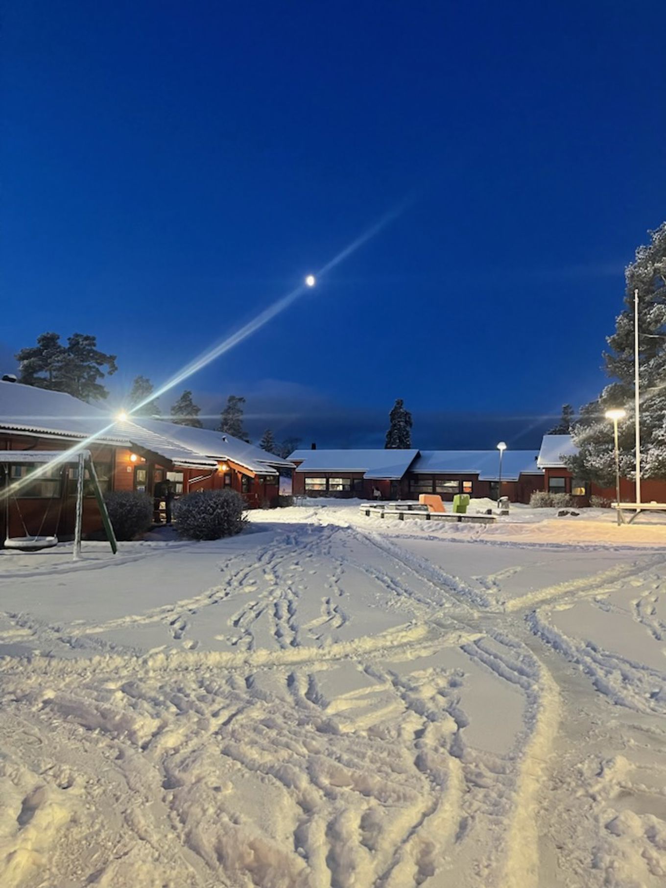 en snødekt skolegård med snødekte tak på bygninger og trær