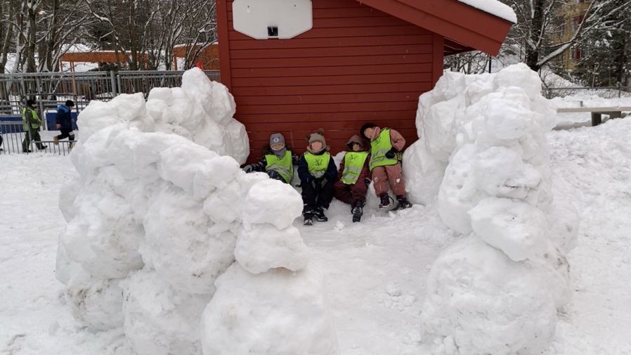 en gruppe barn som poserer med en snøperson