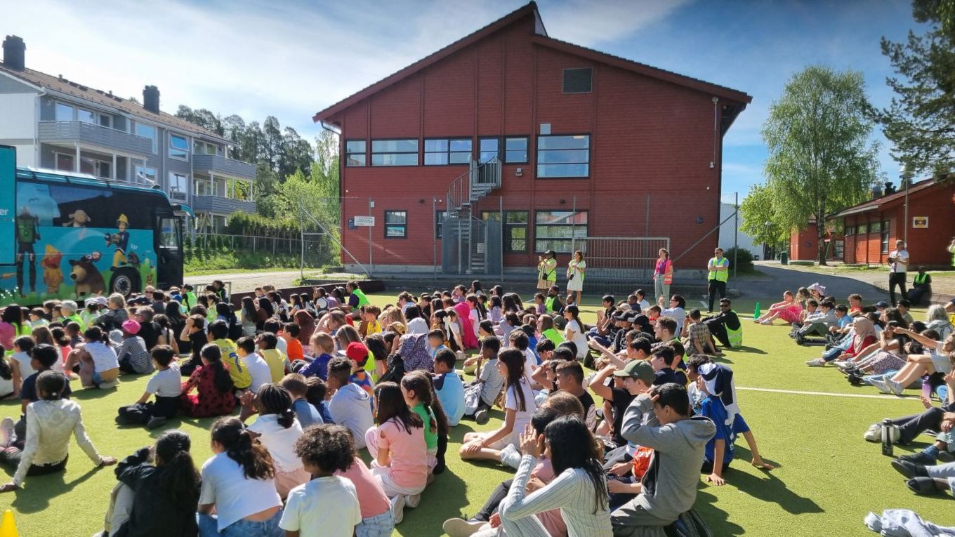 en gruppe mennesker som sitter på gresset foran en bygning