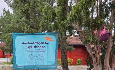 et skilt ved siden av et tre